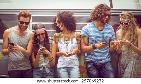 Hipster friends using their phones on a summers day