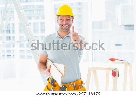 Portrait of happy male carpenter gesturing thumbs up at construction site