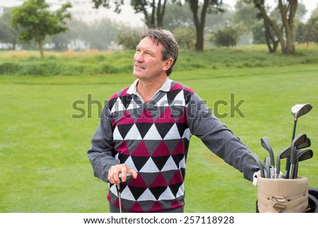 Happy golfer beside his golf bag on a sunny day at the golf course