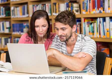 Two college students using laptop in the library