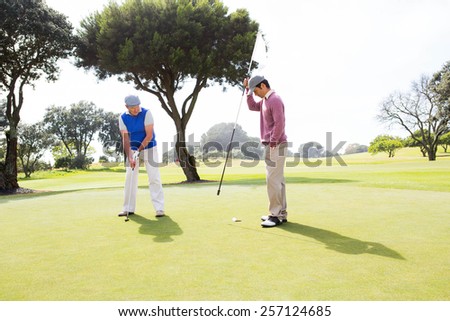Golfer swinging his club with friend at the golf course
