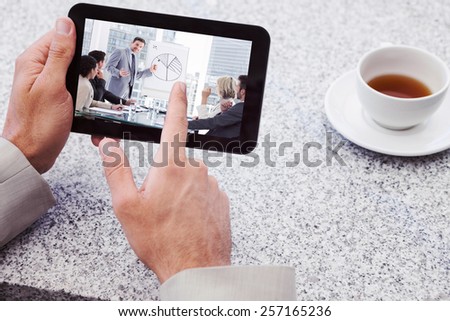 Businessman using small tablet at table against business people in office at presentation