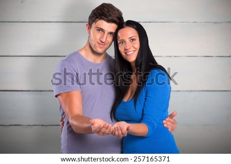 Young couple holding out hands against painted blue wooden planks