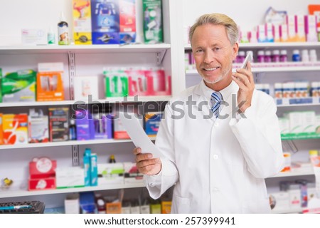Smiling senior phoning while reading prescription in the pharmacy