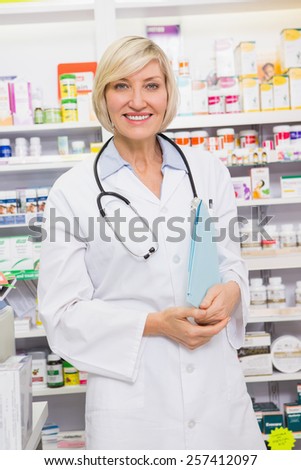 Smiling doctor with stethoscope holding files in the pharmacy