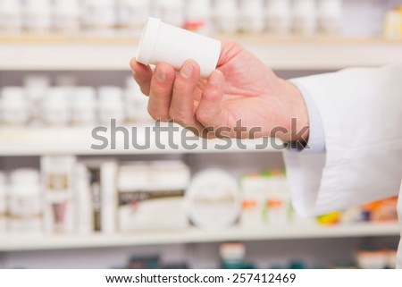 Hand of pharmacist showing medicine jar in the pharmacy