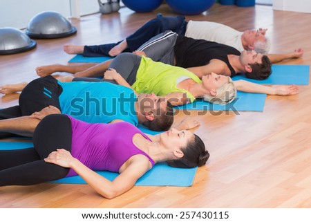 People stretching legs on exercise mats in fitness studio