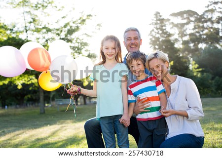 Happy family holding balloons at the park on a sunny day