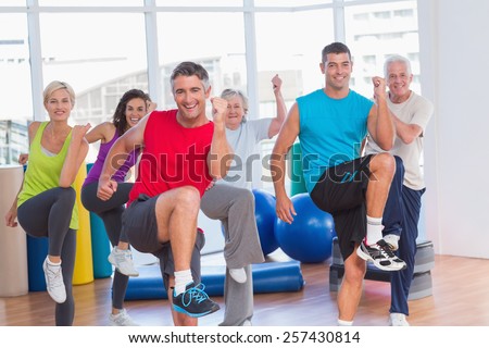 Portrait of fit people performing aerobics exercise in gym class