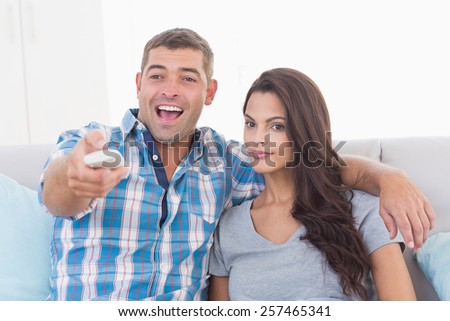 Man changing channels while sitting with woman at home