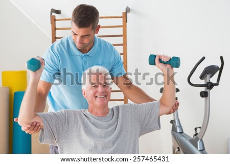 Senior man working out with his trainer in fitness studio