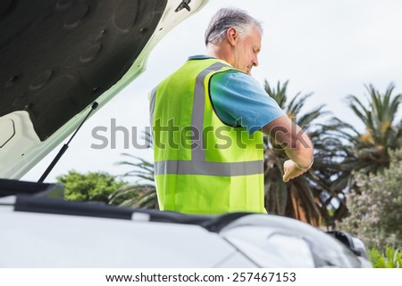 Man checking his watch after breaking down on the road