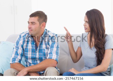 Angry young woman arguing with man while sitting on sofa at home