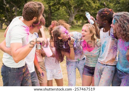 Happy friends throwing powder paint on a sunny day