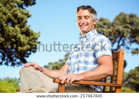 Casual man relaxing on park bench on a sunny day
