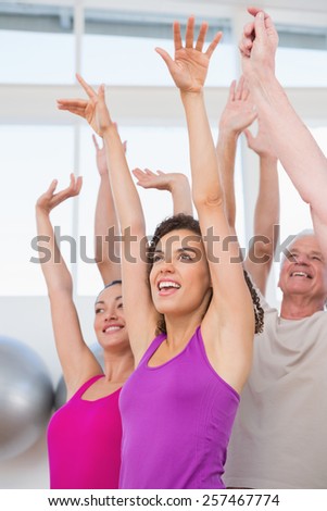 Cheerful friends with hands raised in fitness studio