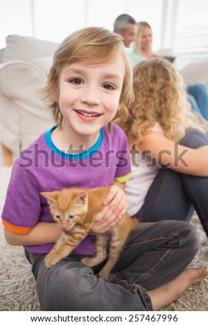 Portrait of happy boy holding kitten while sitting with family in living room