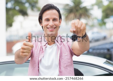 Man smiling and showing thumbs up in front of his car