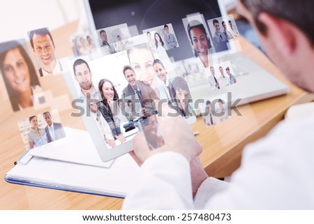 Doctors using laptop and digital tablet in meeting against portrait of a positive team sitting at a table