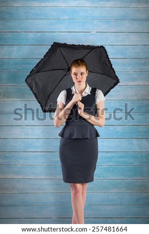 Pretty redhead businesswoman holding umbrella against wooden planks