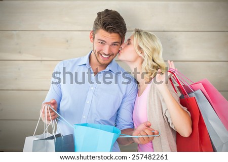 Attractive young couple holding shopping bags against bleached wooden planks background