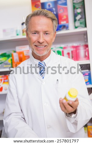 Smiling senior pharmacist holding medicine jar in the pharmacy