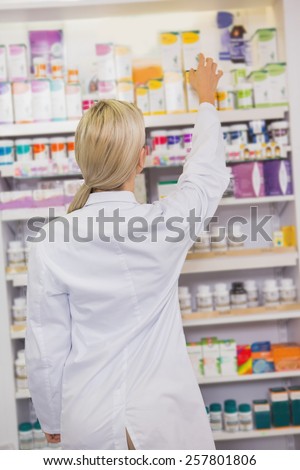 Pretty student taking box from shelf in the pharmacy