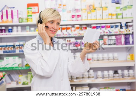 Pharmacist with headphone reading a prescription in the pharmacy