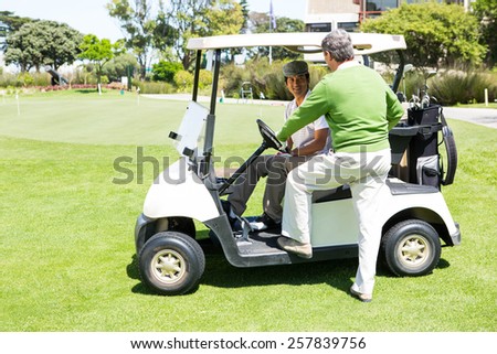 Happy golfing friends setting out on buggy at golf course
