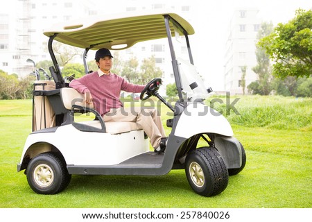 Golfer driving his golf buggy looking at camera at the golf course