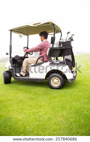 Golfer driving in his golf buggy in golf course