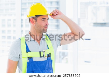 Portrait of manual worker wearing yellow hard hat in bright office