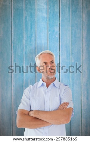 Thinking man posing with arms crossed against wooden planks