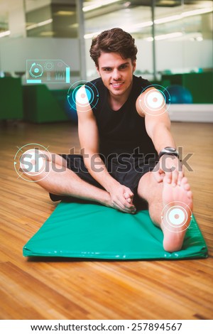 Fit smiling man warming up in fitness studio against fitness interface