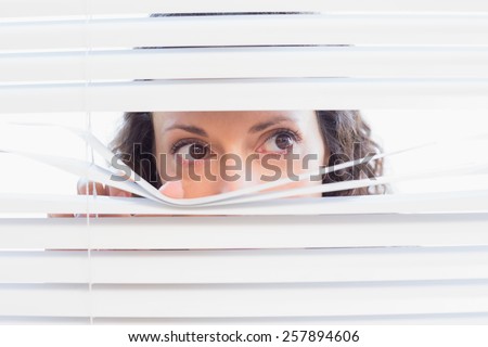 Curious woman looking through blinds in the house