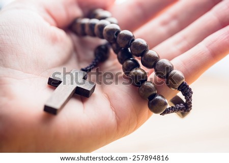 Hand holding wooden rosary beads in close up