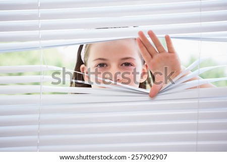 Little girl peeking through blinds from outside