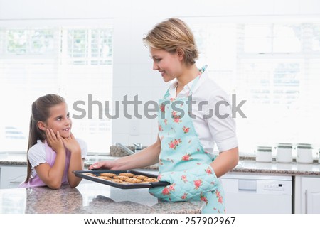 Mother and daughter with hot fresh cookies at home in kitchen