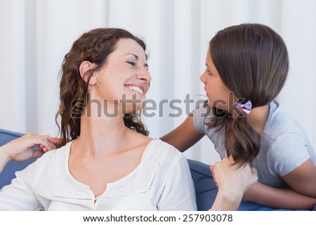 Happy mother and daughter smiling at each other in the living room