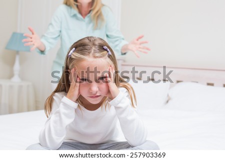 Upset mother scolding her daughter in the bedroom
