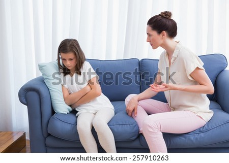 Mother scolding her naughty daughter at home in the living room