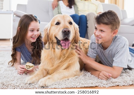 Siblings lying with dog while mother and father sitting on sofa at home