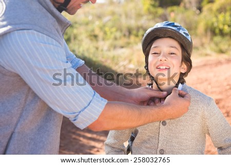 Father clipping on sons helmet on a sunny day