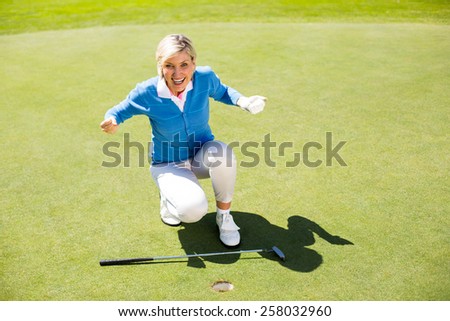 Excited lady golfer cheering on putting green on a sunny day at the golf course