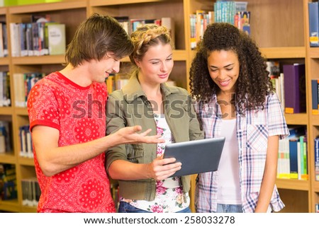 Group of college students using digital tablet in the library