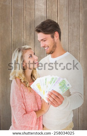 Attractive couple flashing their cash against wooden surface with planks