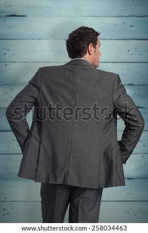 Businessman with hands on hips against wooden planks