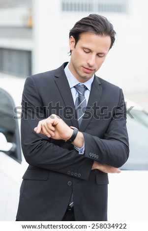 Businessman checking time outside his car