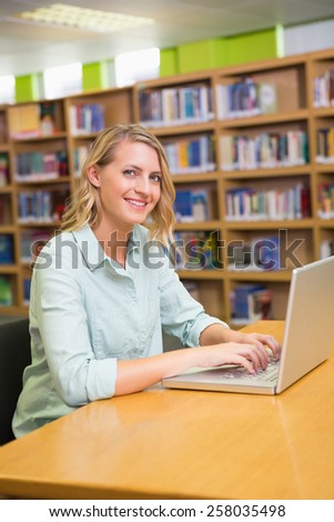 Pretty student studying in the library with laptop at the university