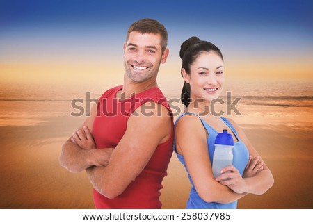 Fit man and woman smiling at camera together against hazy blue sky